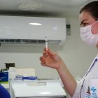 vacinadora mostra vacina sendo preparada para paciente