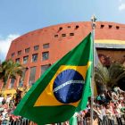 Bandeira do Brasil em exposição durante desfile cívico em Joinville com pessoas assistindo ao fundo