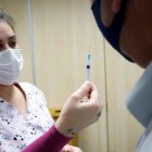 Enfermeira mostra seringa com vacina para homem