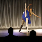 Dois bailarinos estão no palco fazendo uma apresentação para a plateia