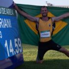 Edenilson com a bandeira do Brasil em frente à placa com marca do recorde
