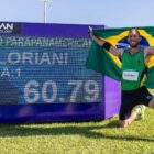 Atleta segura bandeira do Brasil e posa ao lado de placar