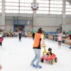 Crianças e adultos patinam na pista de gelo