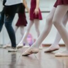Foto de bailarinas em sala de aula fazendo passos de ballet