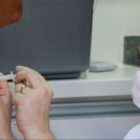 Profissional de saúde com máscara aplica vacina em paciente