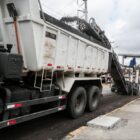 Imagem de um caminhão com asfalto e trabalhador em obra