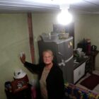 Dona Ingrid, primeira moradora a ter a energia regularizada, acendendo a luz