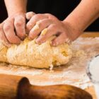 Mãos de pessoa amassam massa de pão