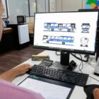 Homem trabalha em computador, olha para tela com desenhos de ônibus