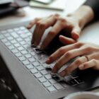 Mão de mulher digita em teclado de computador