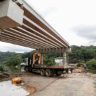 Estrutura de ponte em construção, com caminhão próximo