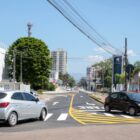 Rua com sinalização viárias nos dois sentidos e dois carros trafegando