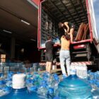 Voluntários carregam caixas com água mineral no caminhão
