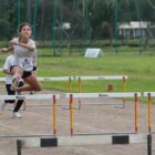 Menina em prova de atletismo com barreira